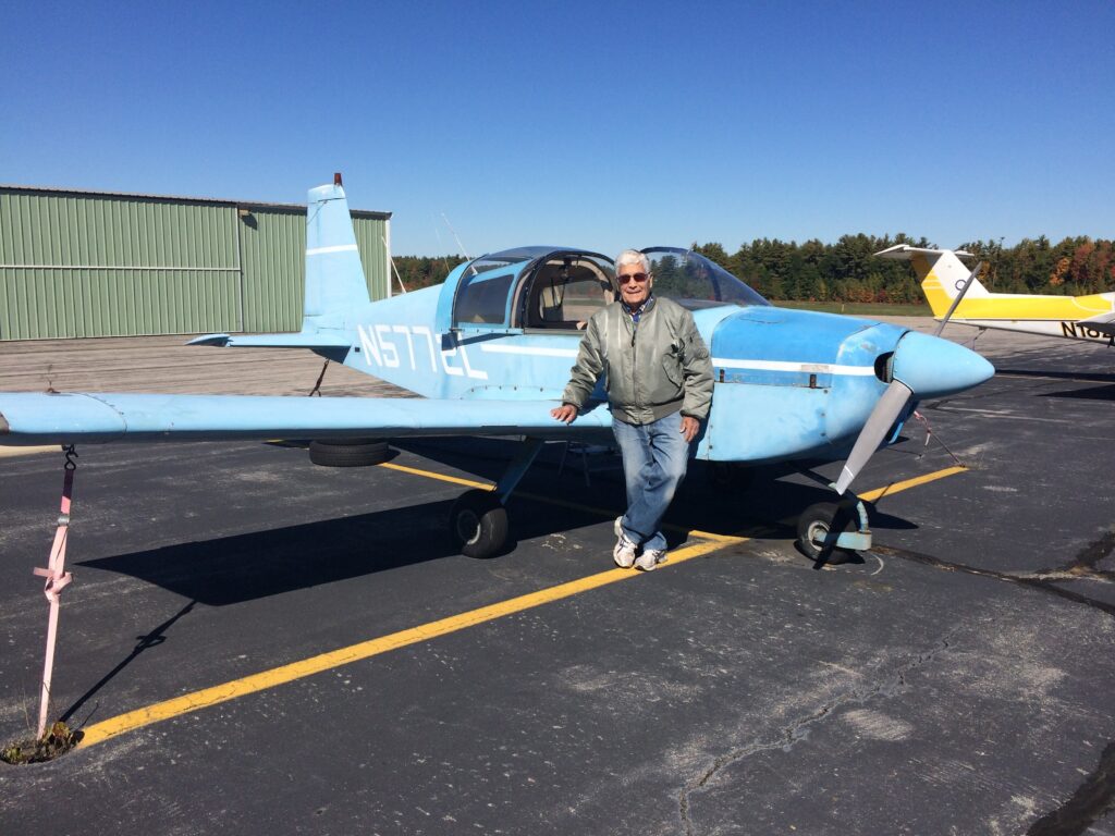 Man standing in front of light blue single prop airplane